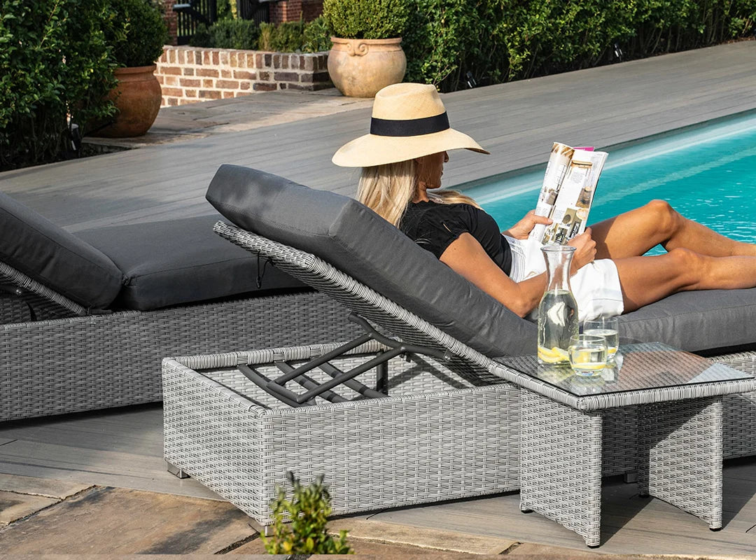 Eine Frau liegt auf einer Rattan Sonnenliege am Pool